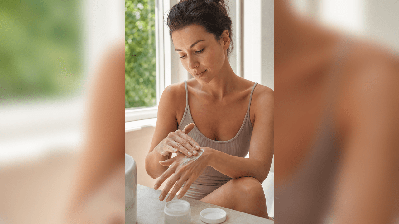 Femeie adultă care aplică cremă de mâini într-o cameră luminoasă de vară